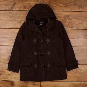 May include: A brown hooded duffel coat with toggle closures and two front pockets. The coat has a soft, suede-like texture and a warm, fur-lined hood. The coat is a classic style for cold weather.