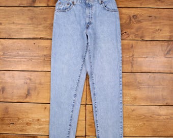 May include: Light blue denim jeans with a classic five-pocket design. The jeans have a straight leg cut and a button and zip closure. The jeans are made of a light wash denim material.