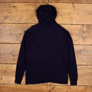 May include: A navy blue long-sleeved hoodie, featuring a hood and a relaxed fit. The garment is made of a soft, solid-colored fabric, suitable for casual wear. The sleeves end with ribbed cuffs.