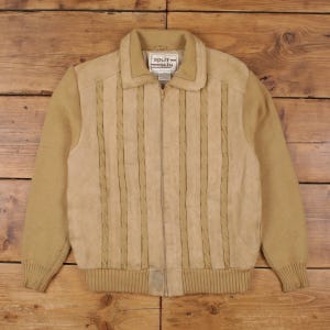 Peut inclure: Veste beige avec fermeture éclair et col. Le devant de la veste est en similicuir avec des détails tressés verticaux. Les manches sont en tricot. L'étiquette indique "SPLIT SKIN".