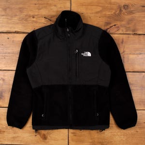 Puede incluir: Chaqueta polar negra con cierre de cremallera completo y cuello alzado. La chaqueta tiene un pequeño bolsillo en el pecho y el logotipo de la marca en la parte superior izquierda del pecho. Las mangas y la parte inferior del cuerpo son de forro polar suave.
