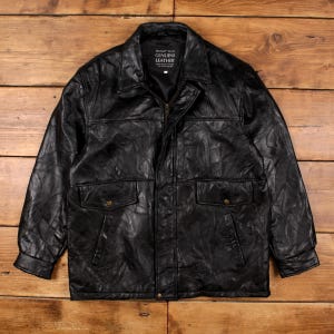 Puede incluir: Chaqueta de cuero negro con diseño de patchwork. Cuenta con cuello, cierre de cremallera y dos bolsillos delanteros con botones. La chaqueta tiene el texto "GENUINE LEATHER" en una etiqueta.