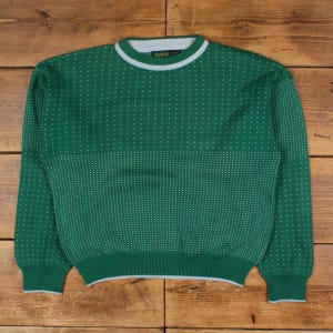 May include: Green knitted sweater with a white dotted pattern and white trim on the collar and cuffs. The sweater has a crew neck and long sleeves. The garment is made of a soft material.