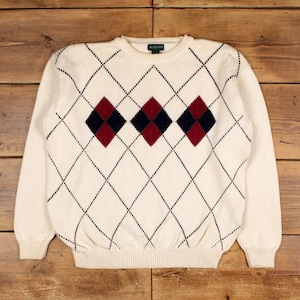 May include: Cream-colored sweater with a classic argyle pattern. The sweater features a repeating diamond design in cream, navy blue, and burgundy. The long-sleeved sweater is made of a soft knit material.