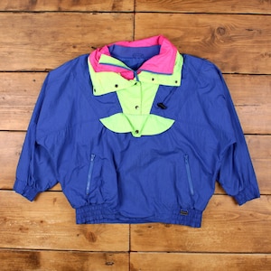 Può includere: Giacca anorak blu vintage con un vivace design a blocchi di colore. La giacca presenta colletto e dettagli verde neon e rosa, due tasche anteriori e un orlo con coulisse. La giacca è realizzata in materiale leggero, possibilmente nylon.