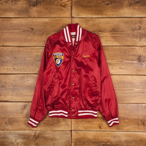 May include: Red satin bomber jacket with white and red striped ribbing. The jacket has a Goodyear Fuel Drag logo on the left chest and the name "Tyler" embroidered on the right chest.