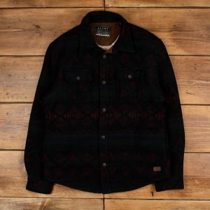 Puede incluir: Chaqueta negra con botones y un patrón geométrico en rojo y gris. La chaqueta tiene dos bolsillos en el pecho y un cuello. El forro interior es de color marrón claro. El nombre de la marca "JACHS" es visible en una etiqueta.