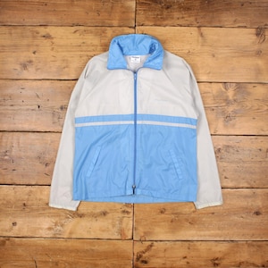 Könnte beinhalten: Hellblaue und graue Windjacke mit durchgehendem Reißverschluss. Die Jacke hat einen hellblauen Kragen und einen horizontalen hellblauen Streifen auf der Brust. Zwei Vordertaschen.