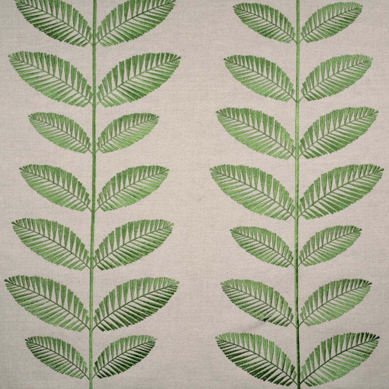 May include: A beige fabric with a repeating pattern of green embroidered leaves. The leaves are stylized and resemble a fern.