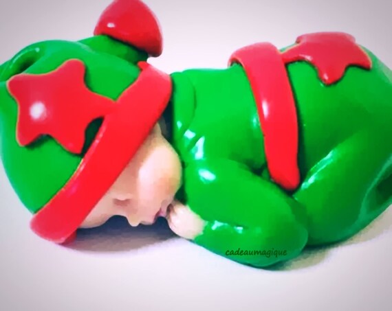 Miniature baby in green leprechaun pajamas in fimo: pregnancy announcement