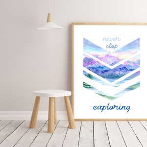 Può includere: Una stampa ad acquerello con un paesaggio montano in tonalità di blu, viola e rosa. Le montagne sono disposte a forma di chevron con il testo "never stop exploring" sotto.