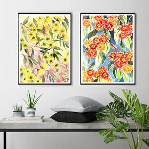 以下が含まれることがあります： 花柄のアレンジメントを描いた額装された水彩画が2点。左側の絵はピンクとグリーンのアクセントがついた黄色の花が描かれている。右側の絵はブルーとグリーンのアクセントがついた赤い花が描かれている。両方の絵は、コンクリート製のテーブルの上に置かれた鉢植えの植物の上にある白い壁に飾られている。