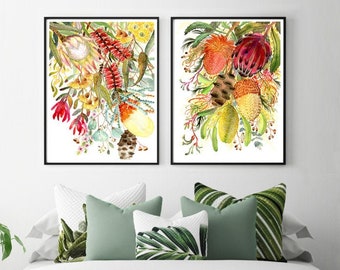 Könnte beinhalten: Zwei gerahmte Aquarellbilder von bunten australischen Wildblumen, darunter rote, gelbe und orangefarbene Blüten. Die Bilder hängen an einer weißen Wand über einem Bett mit grünen und weißen Kissen.