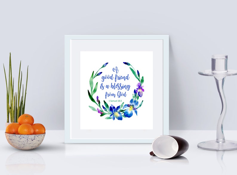 May include: A white framed print with a watercolor floral wreath in shades of blue, green, and purple. The wreath surrounds the text "A good friend is a blessing from God - 1 Samuel 18:1".