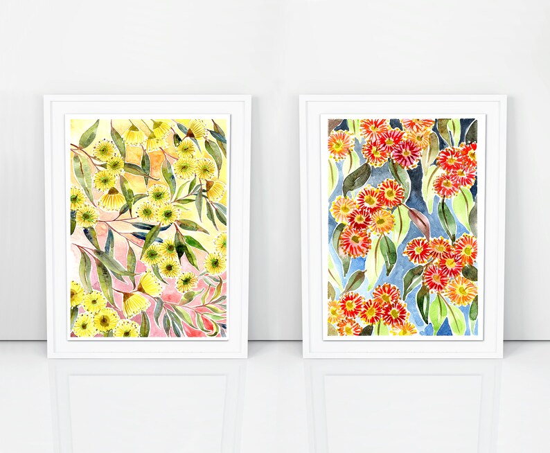 以下が含まれることがあります： 花柄のウォーターカラーの絵画が2つ額装されています。左の絵は、ピンクと黄色の背景に、緑の葉のついた黄色の花が描かれています。右の絵は、青い背景に、緑の葉のついた赤い花が描かれています。