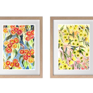 以下が含まれることがあります： 花柄のウォーターカラーの絵画が2つ額装されています。左の絵は、青い背景に赤い花とオレンジの花が緑の葉と一緒に描かれています。右の絵は、ピンクと黄色の背景に黄色い花が緑の葉と一緒に描かれています。
