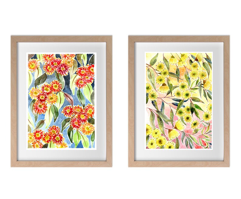 以下が含まれることがあります： 花柄のウォーターカラーの絵画が2つ額装されています。左の絵は、青い背景に赤い花とオレンジの花が緑の葉と一緒に描かれています。右の絵は、ピンクと黄色の背景に黄色い花が緑の葉と一緒に描かれています。