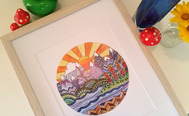 Pu&ograve; includere: Una stampa incorniciata di un'illustrazione circolare colorata che rappresenta una catena montuosa con un sole che sorge alle sue spalle. Le montagne sono viola, blu e verdi, e il sole &egrave; arancione e giallo. L'acqua &egrave; blu e verde, e il cielo &egrave; giallo.