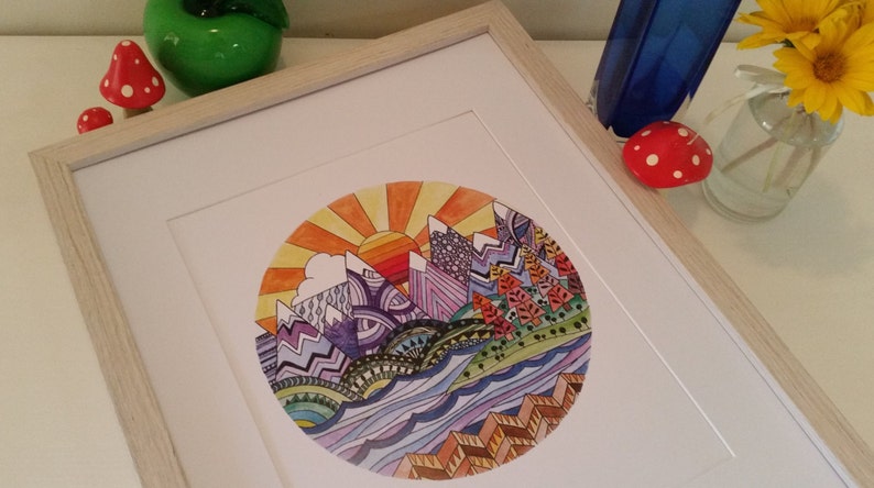 Pu&ograve; includere: Un'illustrazione circolare incorniciata di un paesaggio montano colorato con un sole che sorge sopra le cime. Le montagne sono viola, blu e verdi, e il cielo &egrave; arancione e giallo. L'acqua &egrave; blu e verde, e il primo piano &egrave; marrone e arancione.