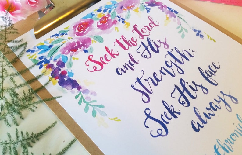 May include: Watercolor floral print with the text "Seek the Lord and His strength; Seek His face always" in a blue and purple calligraphy font.