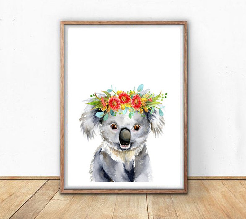 Puede incluir: Una pintura de acuarela de un koala con una corona de flores. El koala es gris y tiene una expresi&oacute;n linda. Las flores de la corona son rojas, amarillas y azules.
