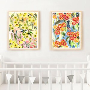 以下が含まれることがあります： 花柄のアレンジメントを描いた水彩画が2枚、額装されています。左側の絵は、ピンクとグリーンのアクセントがついた黄色の花が描かれています。右側の絵は、ブルーとグリーンのアクセントがついた赤い花が描かれています。