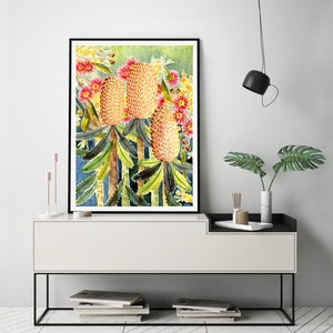 Puede incluir: Pintura acuarela de un grupo de flores de Banksia amarillas y rojas con hojas verdes sobre un fondo azul.