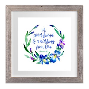 May include: A framed print with a watercolor illustration of a floral wreath with blue and purple flowers. The text inside the wreath reads "A good friend is a blessing from God" with the scripture reference "1 Samuel 18:3".