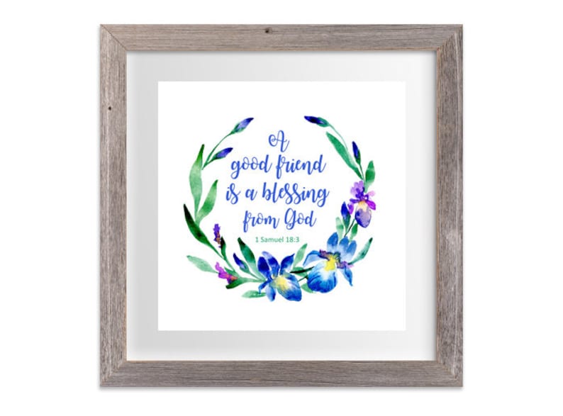 May include: A framed print with a watercolor illustration of a floral wreath with blue and purple flowers. The text inside the wreath reads "A good friend is a blessing from God" with the scripture reference "1 Samuel 18:3".