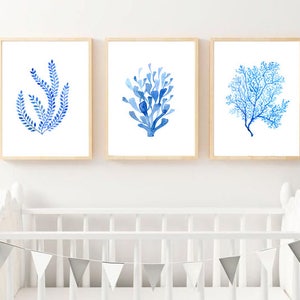Puede incluir: Conjunto de tres l&aacute;minas enmarcadas con acuarelas que representan dise&ntilde;os bot&aacute;nicos azules. Cada l&aacute;mina est&aacute; en un marco de madera clara. La obra de arte incluye im&aacute;genes de algas marinas y corales sobre un fondo blanco.
