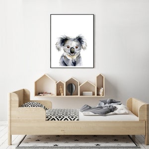 Puede incluir: Una pintura de acuarela de un koala con un fondo blanco. El koala est&aacute; mirando directamente al espectador con una expresi&oacute;n amigable. La pintura est&aacute; enmarcada en un marco negro y est&aacute; colgada en una pared blanca.