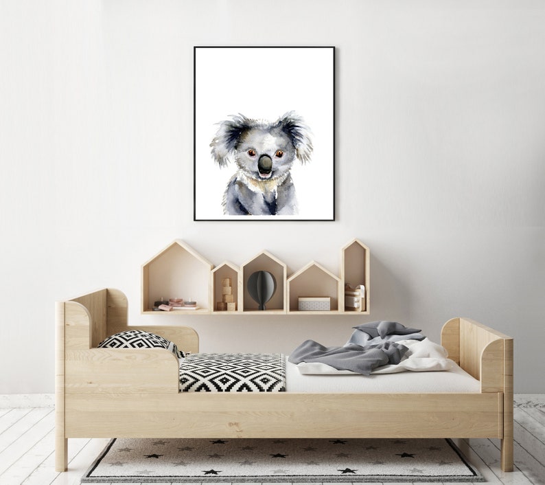 Puede incluir: Una pintura de acuarela de un koala con un fondo blanco. El koala est&aacute; mirando directamente al espectador con una expresi&oacute;n amigable. La pintura est&aacute; enmarcada en un marco negro y est&aacute; colgada en una pared blanca.