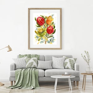 May include: A framed watercolor painting of a bouquet of red and orange protea flowers with green leaves on a white background.