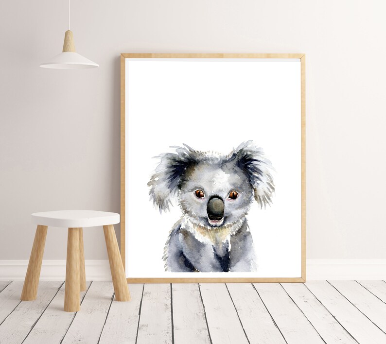 Puede incluir: Una pintura de acuarela de un koala con un pelaje gris claro, grandes ojos negros y una nariz negra. El koala est&aacute; mirando directamente al espectador con una expresi&oacute;n amigable.