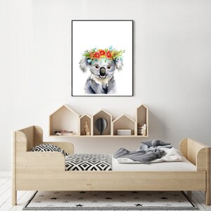 Puede incluir: Una pintura de acuarela de un koala con una corona de flores. El koala es gris con la nariz y los ojos negros. La corona de flores est&aacute; hecha de flores rojas, naranjas, amarillas y azules.