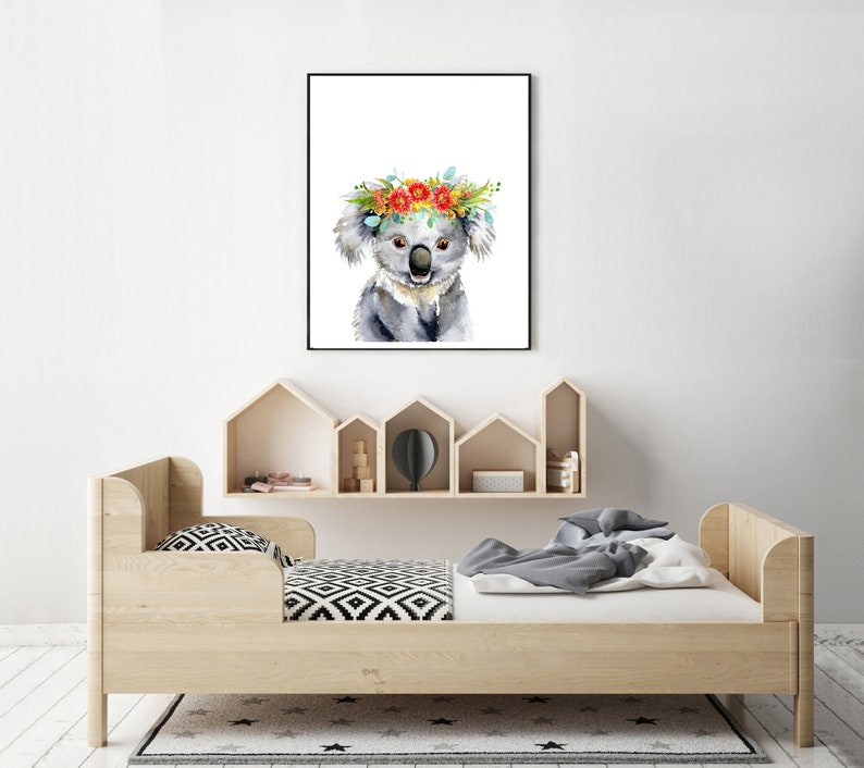 Puede incluir: Una pintura de acuarela de un koala con una corona de flores. El koala es gris con la nariz y los ojos negros. La corona de flores est&aacute; hecha de flores rojas, naranjas, amarillas y azules.