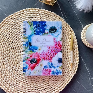 Könnte beinhalten: Ein Blumen-Planer mit weißem Hintergrund und bunten Blumen. Der Planer trägt den Titel "Elise's Planner 2024-2025".