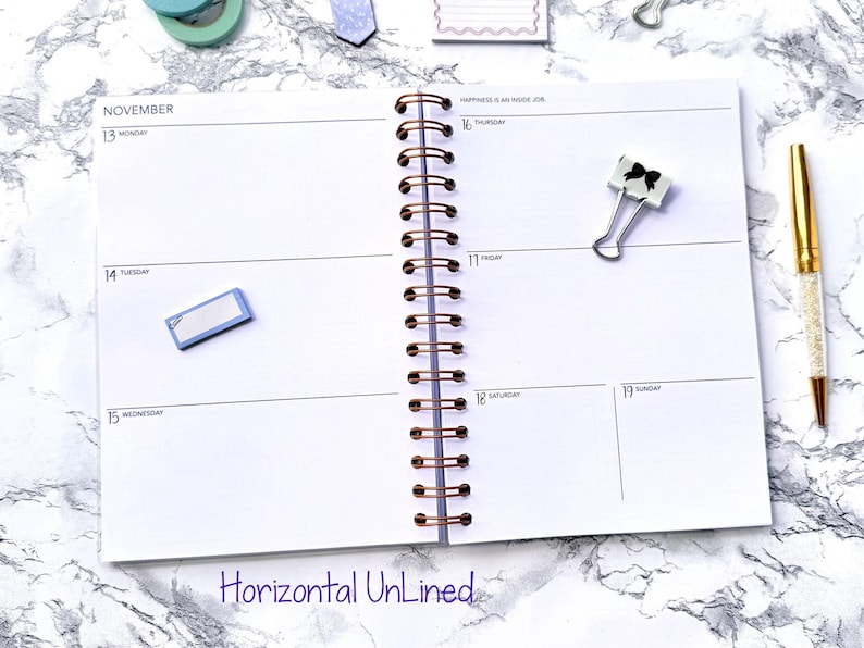 May include: A spiral-bound planner open to a weekly spread for November. The pages are white with a horizontal layout. A gold pen, a binder clip with a black bow, and sticky notes are on the marble surface. The text "Horizontal Unlined" is at the bottom.