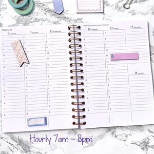 May include: An open spiral-bound planner with a white interior, featuring hourly time slots from 7 am to 8 pm. The planner has a gold pen, decorative tape, and sticky notes. The background is a marble pattern.