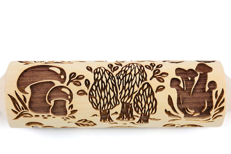 May include: A wooden rolling pin with a brown mushroom design. The rolling pin has a light brown wood color and features three different mushroom designs, including a cluster of mushrooms, a single mushroom, and a group of three mushrooms.