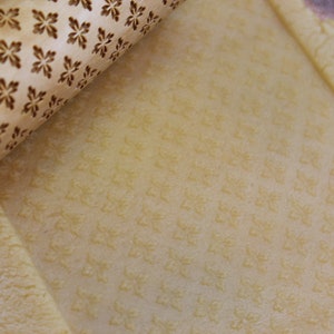 May include: A close-up of a wooden rolling pin with a snowflake pattern. The rolling pin is being used to roll out dough, which is imprinted with the snowflake pattern.