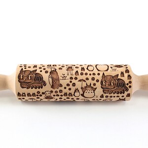 Puede incluir: Un rodillo de madera con un dise&ntilde;o grabado en marr&oacute;n y negro con personajes de la pel&iacute;cula animada Mi Vecino Totoro. El dise&ntilde;o incluye a Totoro, el Catbus y otros personajes de la pel&iacute;cula.