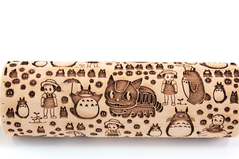 Puede incluir: Un rodillo de madera con fondo marr&oacute;n y un dise&ntilde;o en blanco y negro de personajes de la pel&iacute;cula de animaci&oacute;n "Mi vecino Totoro". El dise&ntilde;o incluye a Totoro, el Catbus y las dos hermanas de la pel&iacute;cula.