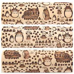 Puede incluir: Un rodillo de madera con un patr&oacute;n repetitivo de un gato de dibujos animados, un personaje de dibujos animados con una cabeza grande y orejas, y un peque&ntilde;o personaje de dibujos animados con un vestido y coletas. El fondo est&aacute; lleno de peque&ntilde;os ojos de dibujos animados.