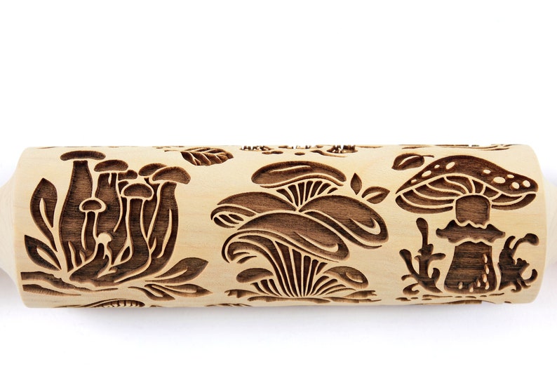 May include: A wooden rolling pin with a carved design of mushrooms and leaves. The rolling pin is made of natural wood and has a light brown color.