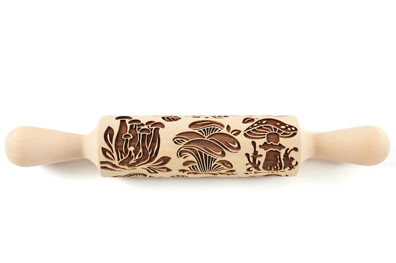 May include: A wooden rolling pin with a carved design of mushrooms. The rolling pin is light brown and has a natural wood finish.