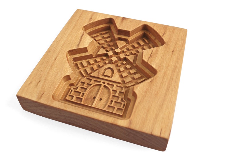Puede incluir: Un cortador de galletas de madera con forma de molino de viento. El cortador tiene un dise&ntilde;o detallado con una puerta y ventanas.