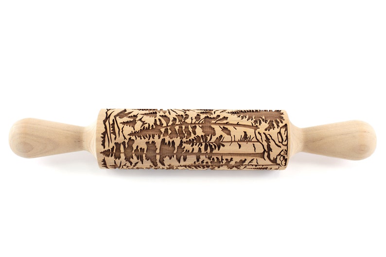 May include: A wooden rolling pin with a detailed forest pattern carved into the rolling surface. The handles are smooth and light-colored, contrasting with the darker, textured design of the rolling surface. Ideal for baking.