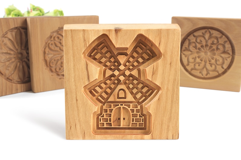 Puede incluir: Cuatro cortadores de galletas de madera, cada uno con un dise&ntilde;o diferente. El cortador del centro presenta un dise&ntilde;o de molino de viento. Los otros cortadores presentan un dise&ntilde;o circular.