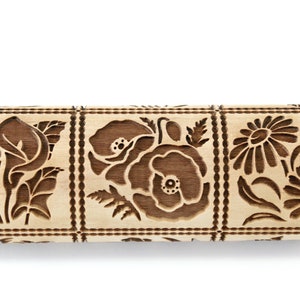 May include: A wooden rolling pin with three engraved designs of flowers. The designs include a cluster of calla lilies, two poppies, and two daisies.